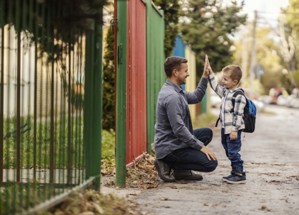 father and son high-fiving outside school