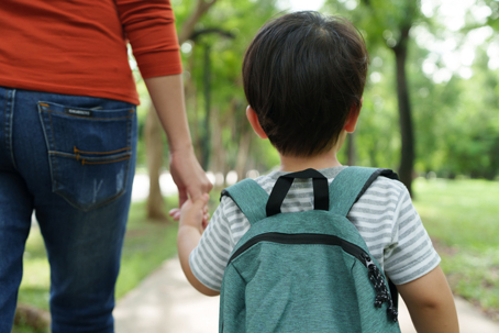 parent holding son's hand as they walk to school